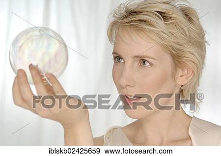 Stock Photo - Blonde woman holding a glass sphere. Fotosearch