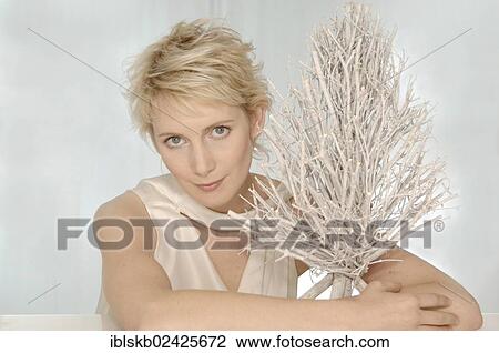 Stock Image - Blonde woman hugging a white brushwood tree. Fotosearch