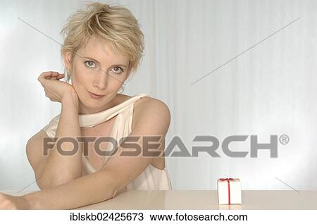 Blonde woman sitting next to a miniature present View Large Photo Image Stock Image - Blonde woman sitting next to a miniature present. Fotosearch