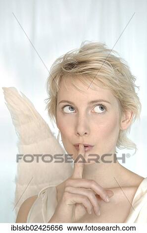 "Blonde woman with angel wings making a silence gesture, looking mysterious" View Large Photo Image Stock Photograph - "Blonde woman with angel wings making a silence gesture, looking mysterious". Fotosearch