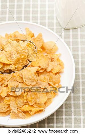 Stock Image - Bowl filled with corn flakes next to a milk bottle. Fotosearch