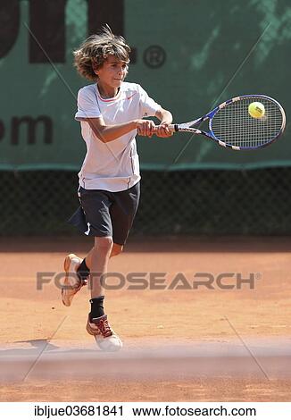 Stock Image - "Boy, 10, playing tennis, hitting with a two-handed backhand, Munich, Upper Bavaria, Bavaria, Germany, Europe". Fotosearch