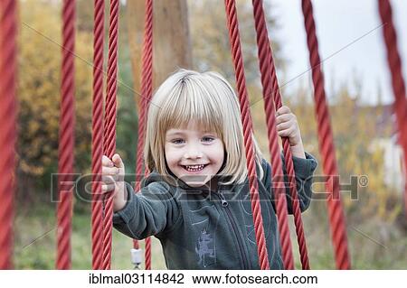 Stock Image - "Boy, 4 years, holding onto ropes whilst balancing, children's playground, Esslingen, Baden-Wurttemberg, Germany, Europe". Fotosearch