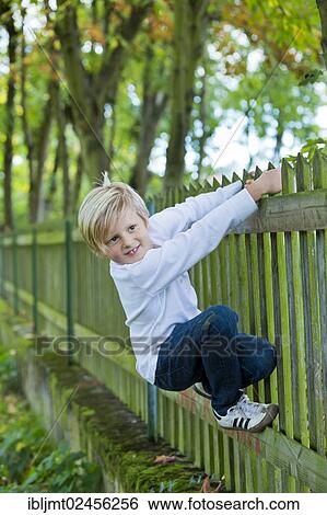 Stock Photograph - "Boy, 7 years old, hanging on to a wooden fence". Fotosearch