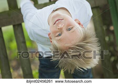 "Boy, 9 years old, hanging on to a wooden fence, upside down" View Large Photo Image Stock Image - "Boy, 9 years old, hanging on to a wooden fence, upside down". Fotosearch