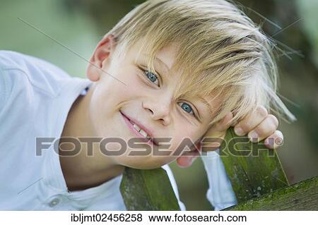 Stock Photo - "Boy, 9 years old, holding on to a wooden fence". Fotosearch