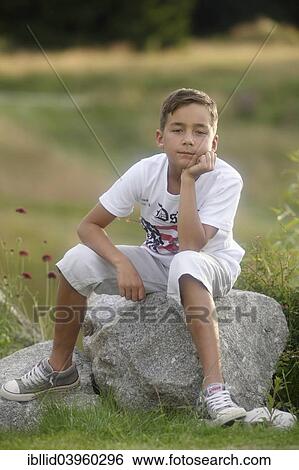 Stock Photograph - "Boy, 9 years old, sitting on rock". Fotosearch
