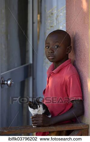 Stock Image - "Boy, 9 years, with a small cat, Tchawa, Leogane, Haiti, North America". Fotosearch