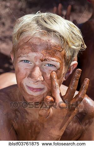 Stock Photography - "Boy applying healing earth, at Platja de Cavalleria Beach, Minorca, Balearic Islands, Spain, Europe". Fotosearch