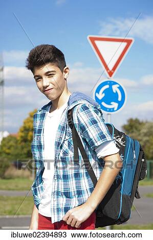 Stock Image - Boy carrying a school bag on the way to school. Fotosearch