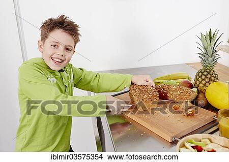 "Boy cutting slices off a whole wheat bread, Germany, Europe" View Large Photo Image Picture - "Boy cutting slices off a whole wheat bread, Germany, Europe". Fotosearch