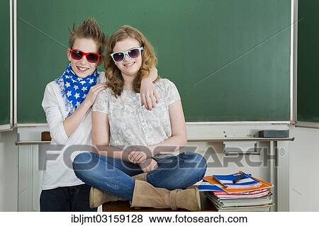 Stock Photo - "Boy embracing a girl in the classroom, both are wearing sunglasses, Germany, Europe". Fotosearch