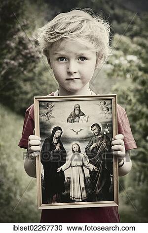 Stock Image - "Boy holding a Christian image of saints, with Jesus, Mary and Joseph, pneuma". Fotosearch