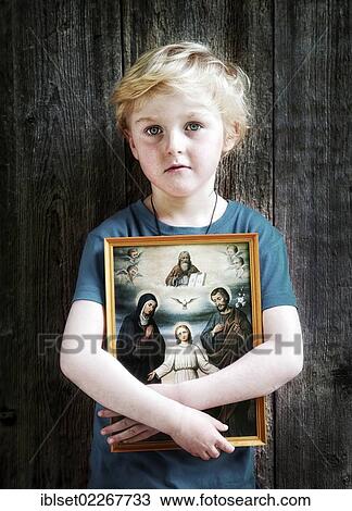 Stock Image - "Boy holding a Christian image of saints, with Jesus, Mary and Joseph, pneuma". Fotosearch