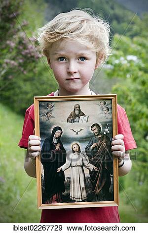 Stock Photo - "Boy holding a Christian image of saints, with Jesus, Mary and Joseph, pneuma". Fotosearch