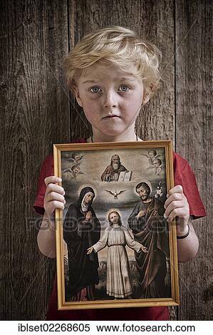 Stock Photography - "Boy holding a Christian image of saints, with Jesus, Mary and Joseph, pneuma". Fotosearch