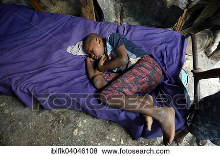 "Boy is sleeping on a bed in barracks, Camp Icare for earthquake refugees, 5 years after the 2010 earthquake, Fort National, Port-au-Prince, Haiti, North America" View Large Photo Image Stock Photo - "Boy is sleeping on a bed in barracks, Camp Icare for earthquake refugees, 5 years after the 2010 earthquake, Fort National, Port-au-Prince, Haiti, North America". Fotosearch