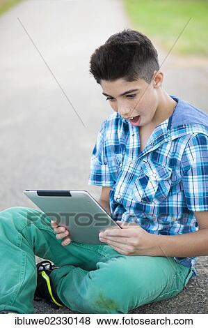 Stock Photo - Boy playing on his tablet computer. Fotosearch