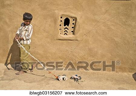 "Boy playing with a home-made toy cars outside a mud house, Wuste Thar, Rajasthan, India, Asia" View Large Photo Image Stock Photo - "Boy playing with a home-made toy cars outside a mud house, Wuste Thar, Rajasthan, India, Asia". Fotosearch