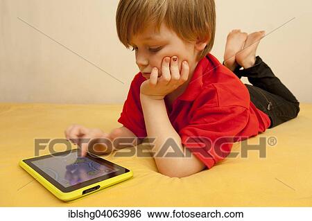 Boy playing with a tablet PC View Large Photo Image Stock Photograph - Boy playing with a tablet PC. Fotosearch