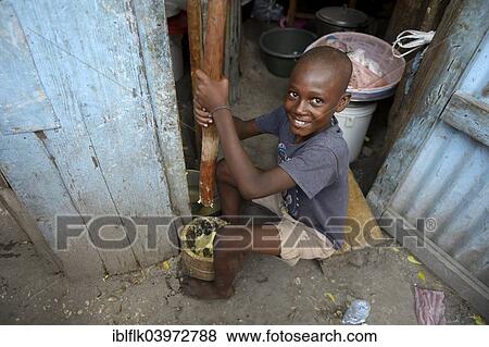 "Boy pounding corn into flour in a mortar, making flatbread, Camp Icare for earthquake refugees, Fort National, Port-au-Prince, Haiti, North America" View Large Photo Image Stock Photo - "Boy pounding corn into flour in a mortar, making flatbread, Camp Icare for earthquake refugees, Fort National, Port-au-Prince, Haiti, North America". Fotosearch