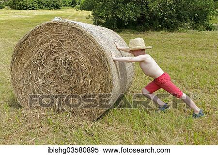 "Boy pushing a bale of straw, Germany, Europe" View Large Photo Image Stock Photography - "Boy pushing a bale of straw, Germany, Europe". Fotosearch