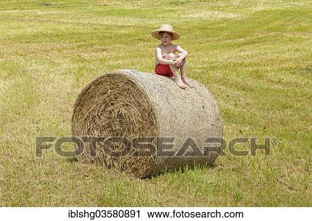 Stock Image - "Boy sitting on a bale of straw, Germany, Europe". Fotosearch
