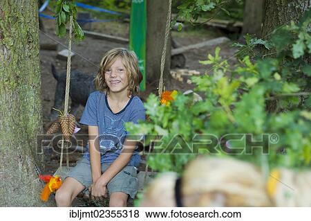 "Boy sitting on a swing, at the forest kindergarten, Ilmmuenster, Bavaria, Germany, Europe" View Large Photo Image Stock Photo - "Boy sitting on a swing, at the forest kindergarten, Ilmmuenster, Bavaria, Germany, Europe". Fotosearch