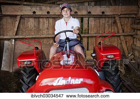 Stock Photo - "Boy sitting on a vintage tractor, Reith im Alpbachtal, Kufstein District, North Tirol, Tirol, Austria, Europe". Fotosearch