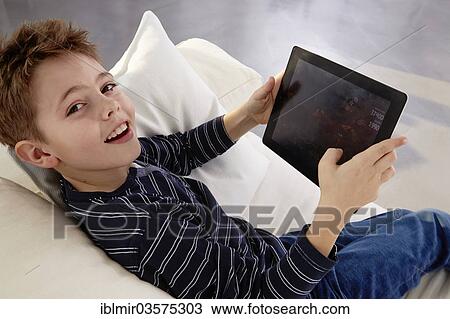 "Boy sitting with tablet pc on a sofa, Germany, Europe" View Large Photo Image Stock Image - "Boy sitting with tablet pc on a sofa, Germany, Europe". Fotosearch