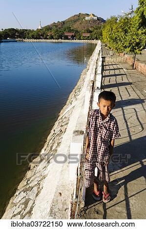 "Boy standing at the canal at the Royal Palace in front of Mandalay Hill, Mandalay, Mandalay Division, Myanmar, Burma, Asia" View Large Photo Image Stock Image - "Boy standing at the canal at the Royal Palace in front of Mandalay Hill, Mandalay, Mandalay Division, Myanmar, Burma, Asia". Fotosearch