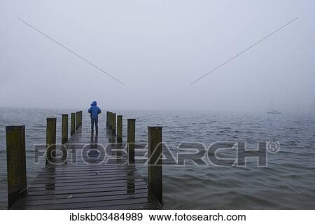 "Boy standing on a wooden jetty in the fog, Starnberger See, Starnberg, Upper Bavaria, Bavaria, Germany, Europe" View Large Photo Image Stock Photo - "Boy standing on a wooden jetty in the fog, Starnberger See, Starnberg, Upper Bavaria, Bavaria, Germany, Europe". Fotosearch