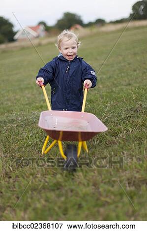 "Boy, toddler, 1. 5 years, pushing a wheelbarrow across a meadow, Germany, Europe" View Large Photo Image Stock Photo - "Boy, toddler, 1. 5 years, pushing a wheelbarrow across a meadow, Germany, Europe". Fotosearch