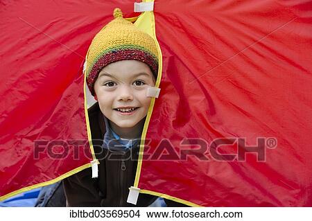 "Boy with a knited cap looking out of a red tent, happy, Germany, Europe" View Large Photo Image Picture - "Boy with a knited cap looking out of a red tent, happy, Germany, Europe". Fotosearch