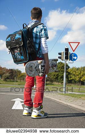 Boy with a school bag and a skateboard on a street View Large Photo Image Stock Photo - Boy with a school bag and a skateboard on a street. Fotosearch