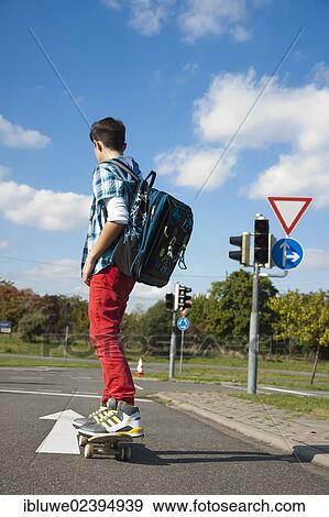 Boy with a school bag and a skateboard on a street View Large Photo Image Stock Photo - Boy with a school bag and a skateboard on a street. Fotosearch