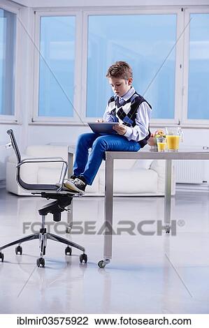 "Boy with a tablet PC sitting on a desk, Munich, Upper Bavaria, Bavaria, Germany, Europe" View Large Photo Image Stock Image - "Boy with a tablet PC sitting on a desk, Munich, Upper Bavaria, Bavaria, Germany, Europe". Fotosearch