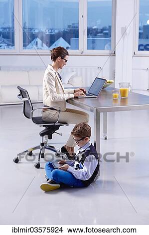 "Boy with a tablet PC sitting on the floor, mother sitting at desk and working on laptop, Munich, Upper Bavaria, Bavaria, Germany, Europe" View Large Photo Image Picture - "Boy with a tablet PC sitting on the floor, mother sitting at desk and working on laptop, Munich, Upper Bavaria, Bavaria, Germany, Europe". Fotosearch