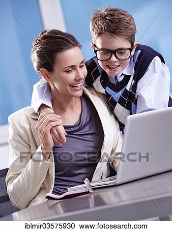 Stock Image - "Boy with glasses puts his arm around his mother, both looking at a laptop, Munich, Upper Bavaria, Bavaria, Germany, Europe". Fotosearch