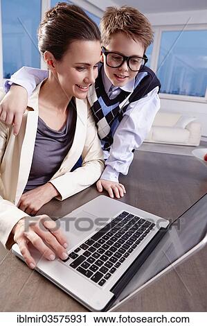 "Boy with glasses puts his arm around his mother, both looking at a laptop, Munich, Upper Bavaria, Bavaria, Germany, Europe" View Large Photo Image Stock Image - "Boy with glasses puts his arm around his mother, both looking at a laptop, Munich, Upper Bavaria, Bavaria, Germany, Europe". Fotosearch