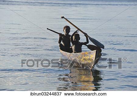 Stock Photo - "Boys in a canoe in backlight, Marovo Lagoon, Western Province, Solomon Islands, Oceania". Fotosearch