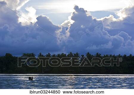 Stock Image - "Boys in a canoe in the Marovo Lagoon, in backlight, Marovo Lagoon, Western Province, Solomon Islands, Oceania". Fotosearch