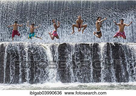Stock Photograph - "Boys jumping in a waterfall and having fun, Bali, Indonesia, Asia". Fotosearch