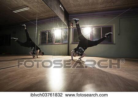 Stock Image - "Breakdancer dancing in front of a mirror wall, Terfens, Tyrol, Austria, Europe". Fotosearch