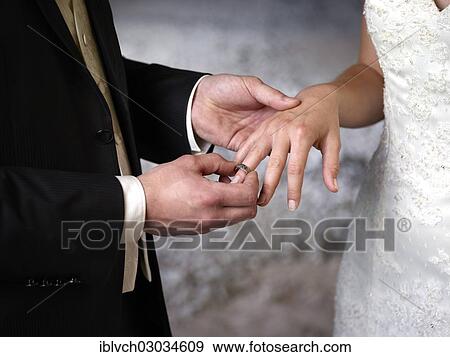 "Bride and groom, groom putting the ring on the bride's finger, Austria, Europe" View Large Photo Image Stock Photo - "Bride and groom, groom putting the ring on the bride's finger, Austria, Europe". Fotosearch