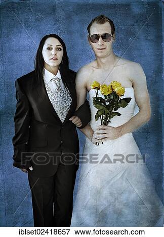 Stock Photo - Bride wearing a suit and a groom wearing a wedding dress with sunglasses and yellow roses. Fotosearch