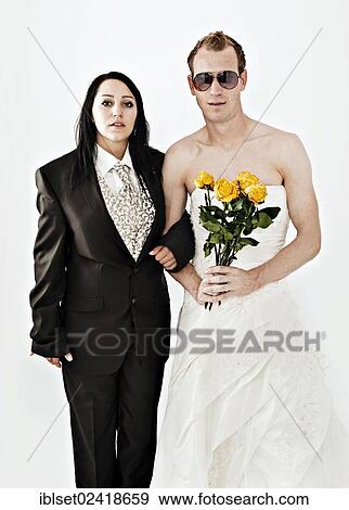 Stock Photo - Bride wearing a suit and a groom wearing a wedding dress with sunglasses and yellow roses. Fotosearch