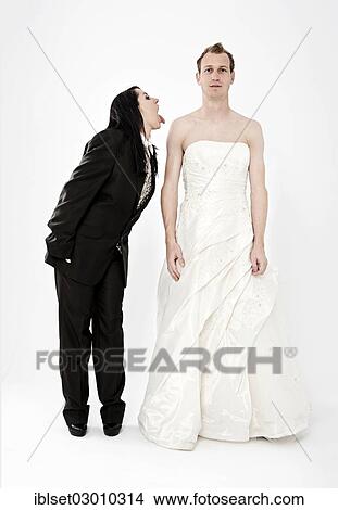 Picture - "Bride wearing a suit poking her tongue out at the groom wearing a wedding dress, exchange of wedding clothing, Austria, Europe". Fotosearch
