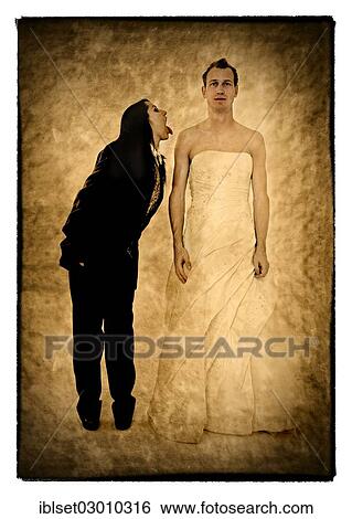 Stock Photograph - "Bride wearing a suit poking her tongue out at the groom wearing a wedding dress, exchange of wedding clothing, Austria, Europe". Fotosearch