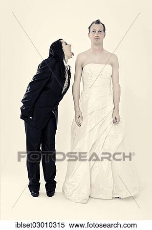 Stock Photography - "Bride wearing a suit poking her tongue out at the groom wearing a wedding dress, exchange of wedding clothing, Austria, Europe". Fotosearch